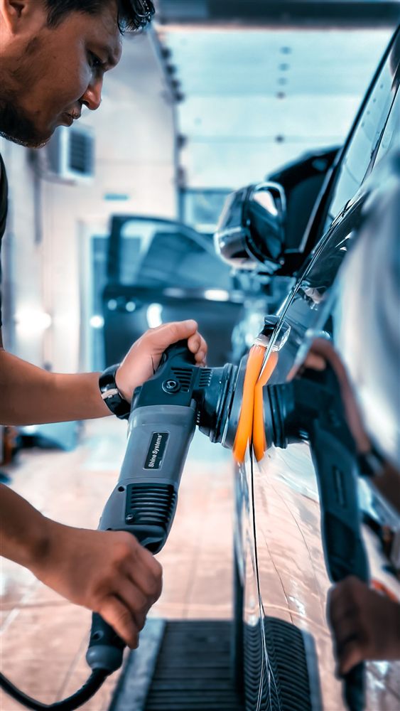 Machine polisher compounding a black car door panel